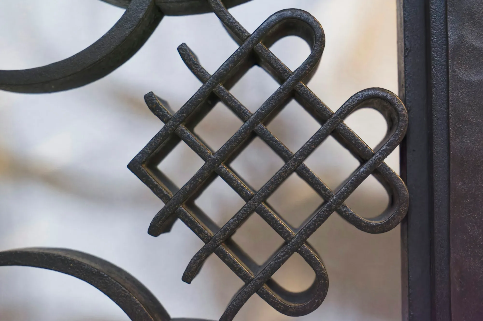 Close-up of a woven knot pattern in a black wrought iron gate