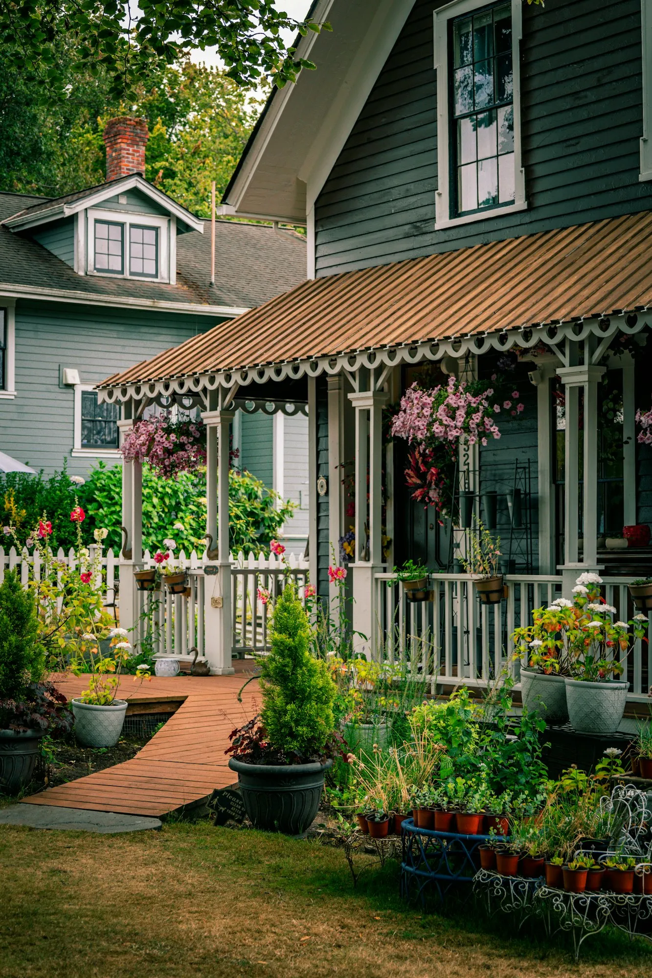 White picket fence and flower pots along the porch of a green house
