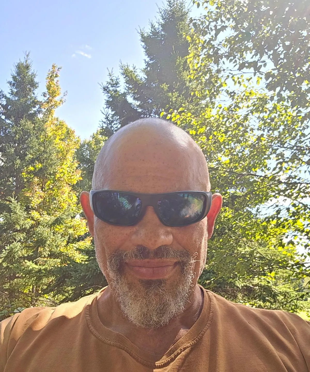 Alexander Medina, the owner, in sunglasses and a brown shirt, standing in front of trees