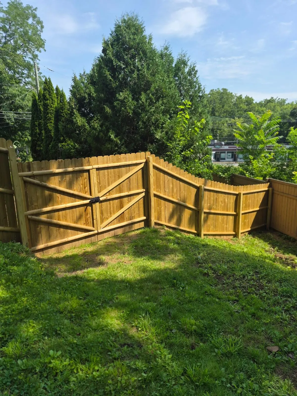 Wood privacy fence with a double gate stepping down a grassy slope