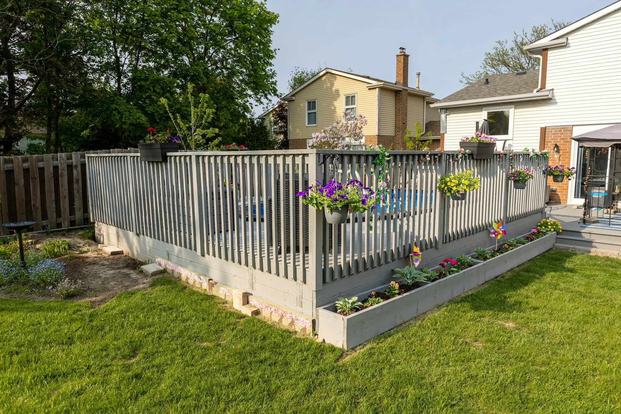 Raised deck with gray railings and flower boxes in a fenced backyard